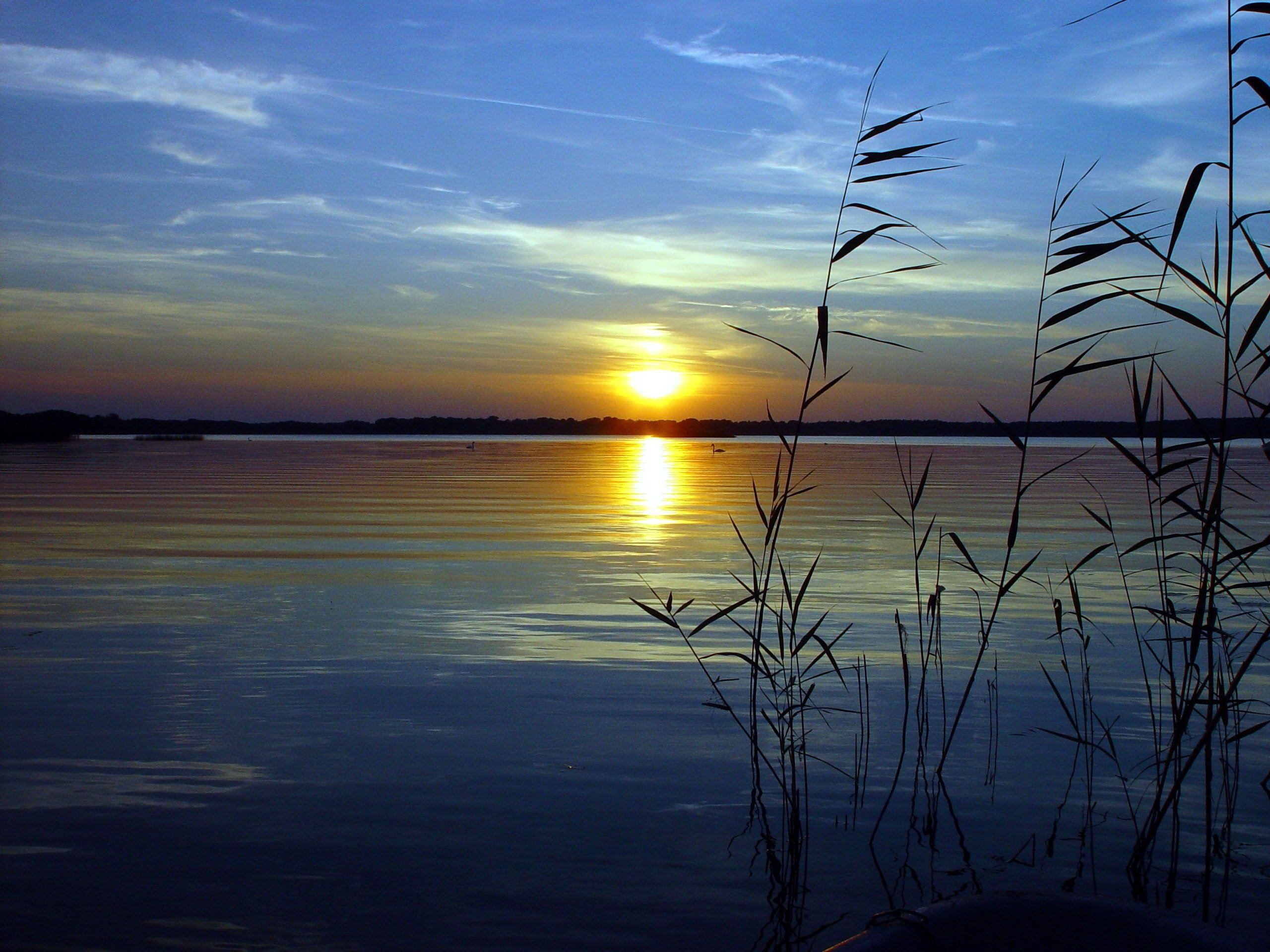Чуть колышется. Закат на озере. Отражение солнца в воде. Рассвет на озере. Закат над озером.